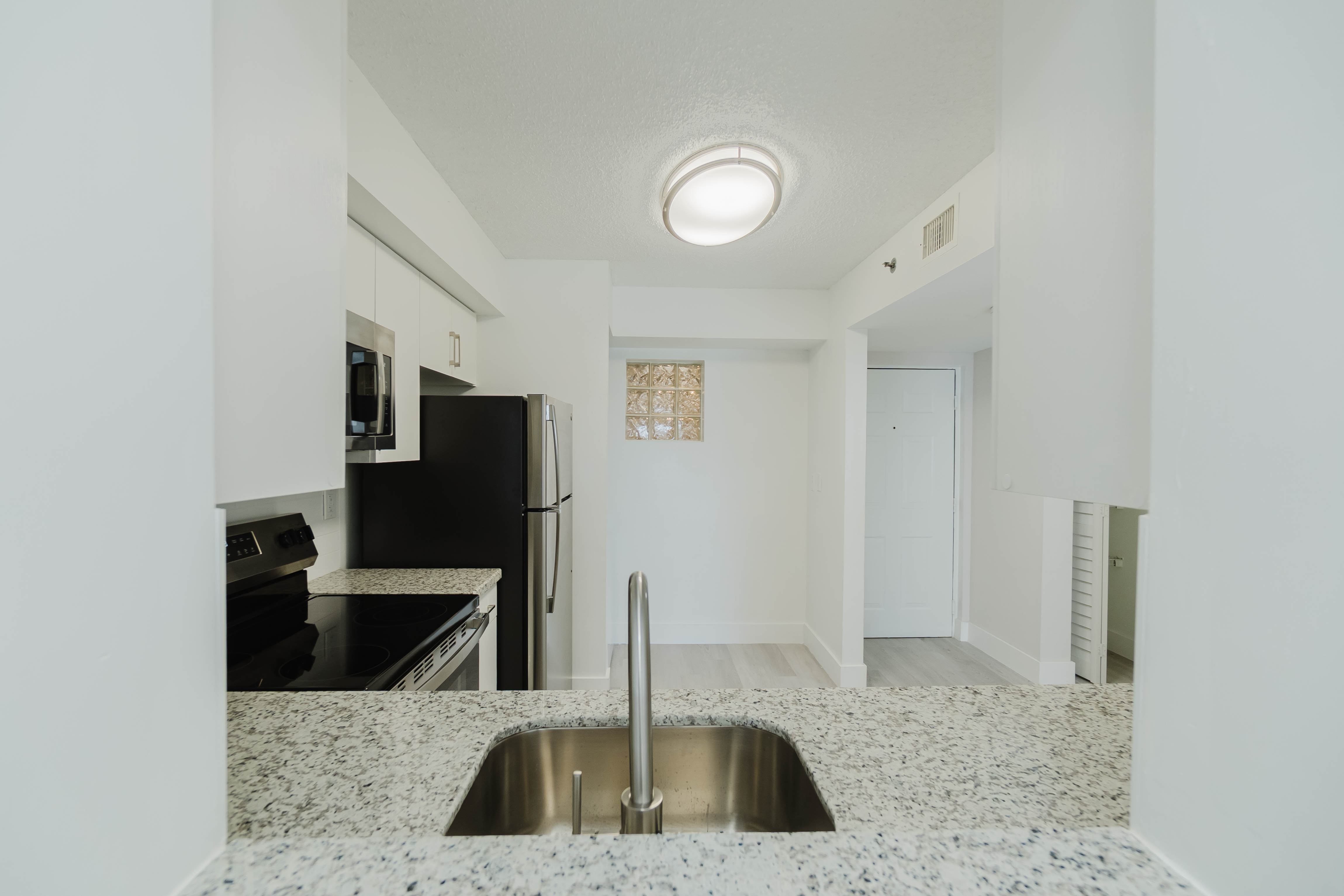 A kitchen with a sink and a refrigerator.